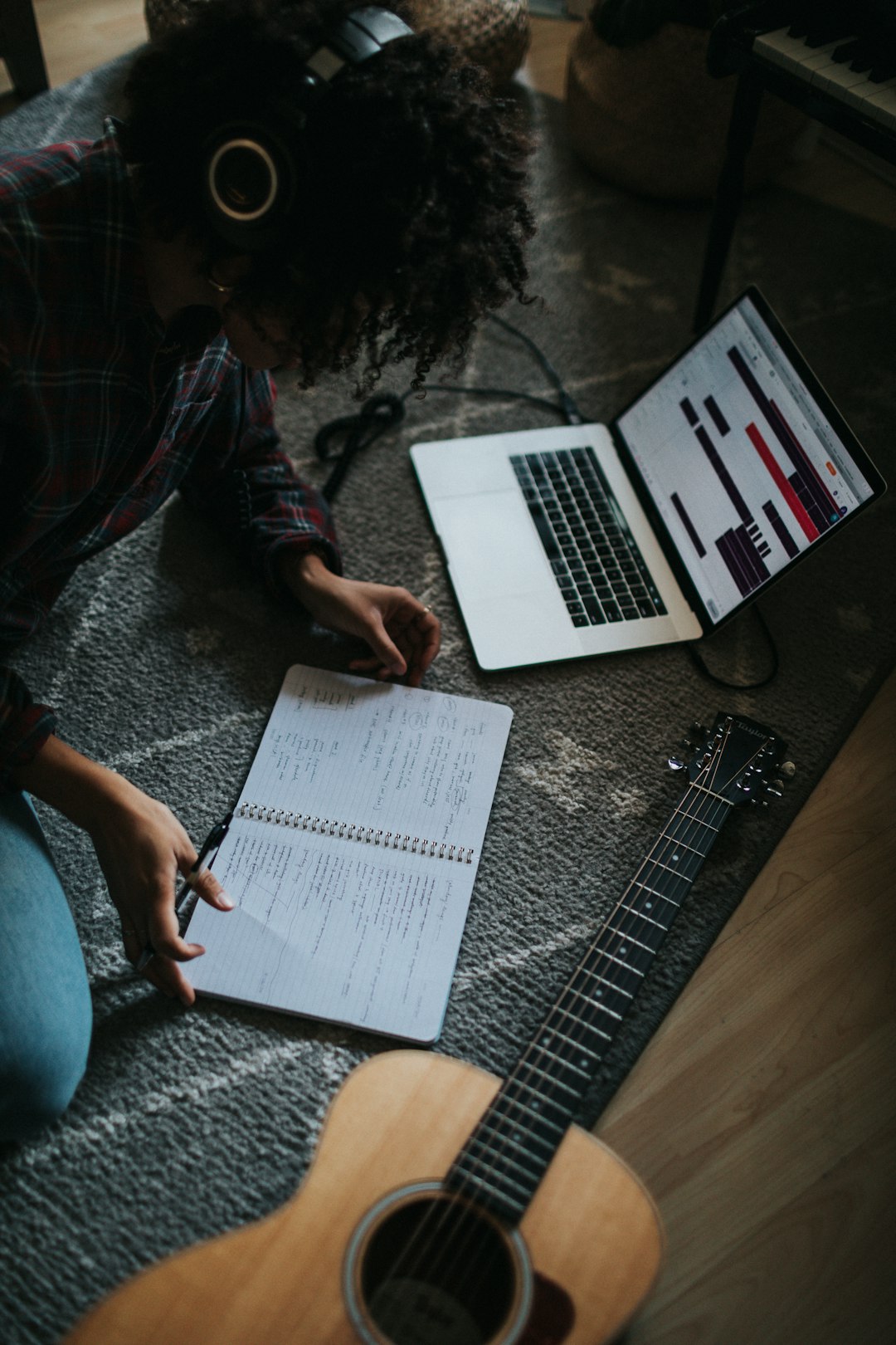 Background: A Brief History of Guitars by Guitar Brands person in black jacket sitting on floor while writing on notebook