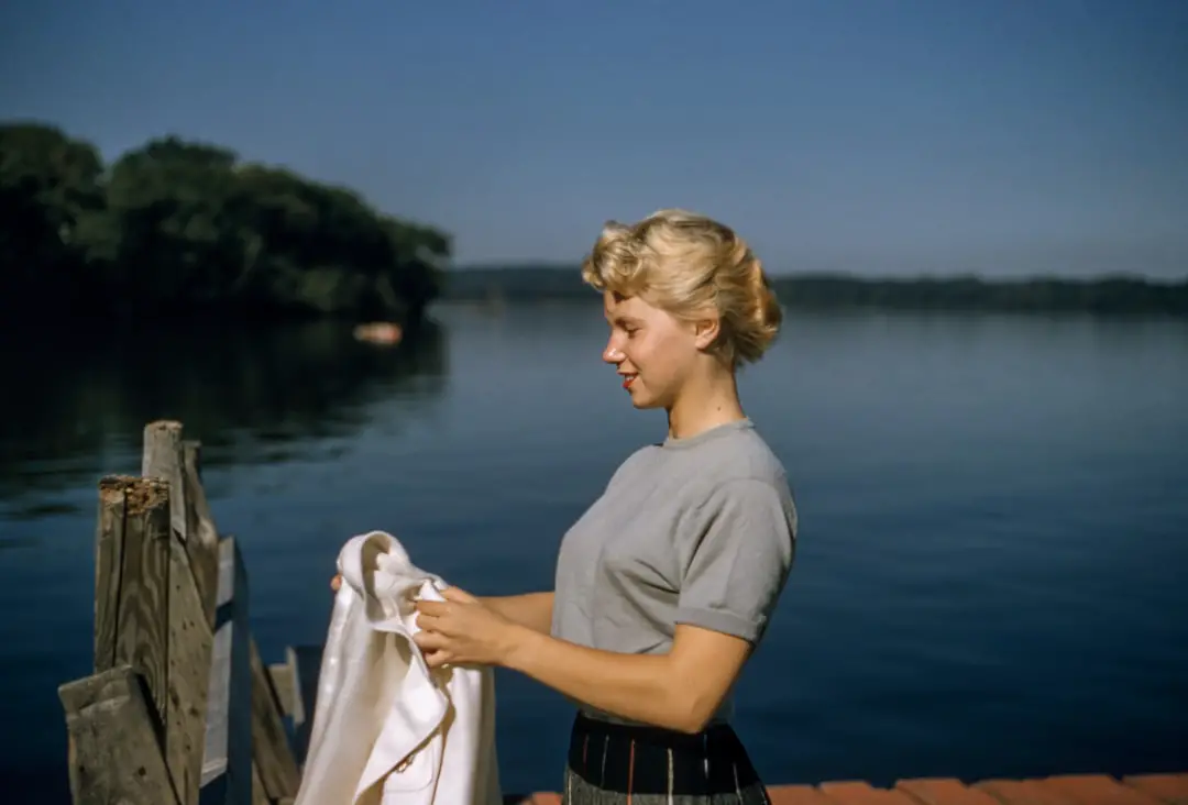 Vintage Hair by Guitar Brands woman holding white textile standing beside body of water